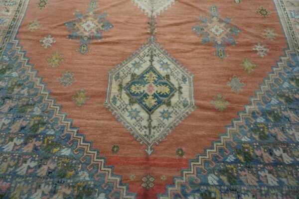 Close-up of a salmon-colored rug with geometric blue and white medallions, by rugs on net