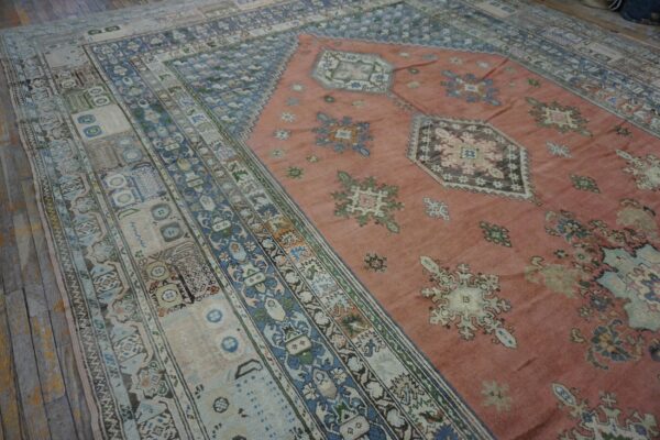 Close-up view of a vintage rug with a salmon field and intricate blue and beige borders by rugs on net