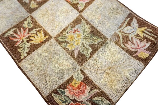 Close-up of a hooked rug featuring a checkerboard pattern with floral motifs in brown diamonds, by rugs on net. By rugs on net