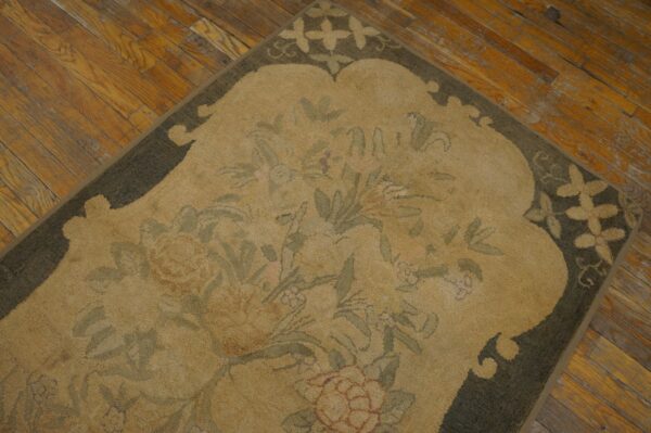 Close-up of a vintage scalloped chinese art deco rug showing the tan field, green floral design, and dark scalloped edge on a wood floor by rugs on net