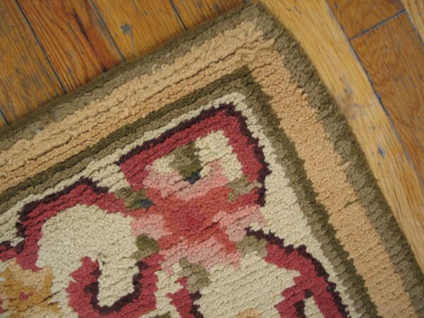 Close-up of a floral pattern rug border with beige, red, and green tones on a wood floor by rugs on net. By rugs on net