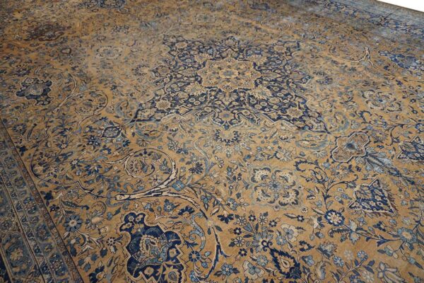 Close-up view of a faded antique persian rug with gold and navy blue floral patterns by rugs on net. By rugs on net