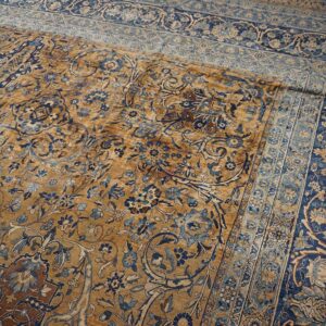 Close-up of a faded gold and blue floral pattern on an antique rug by Rugs On Net