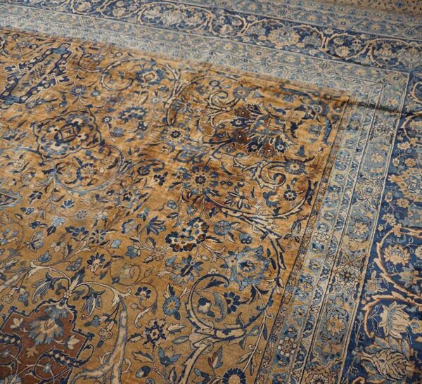 Close-up of a faded gold and blue floral pattern on an antique rug by rugs on net