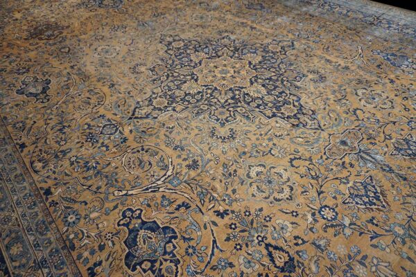 Close-up of an aged, faded persian rug with intricate blue floral patterns on a tan ground, by rugs on net