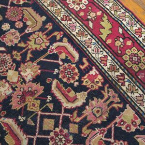 Close-up detail of a dark blue field rug with intricate floral patterns in pink, gold, and red, featuring a detailed border section by Rugs On Net. by Rugs On Net