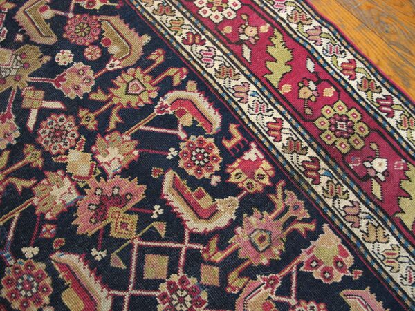 Close-up detail of a dark blue field rug with intricate floral patterns in pink, gold, and red, featuring a detailed border section by rugs on net. By rugs on net