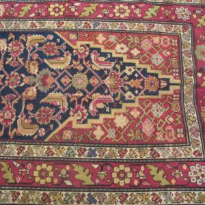Close-up of a richly patterned rug with a dark blue field and red borders, featuring geometric and stylized floral motifs, by Rugs On Net