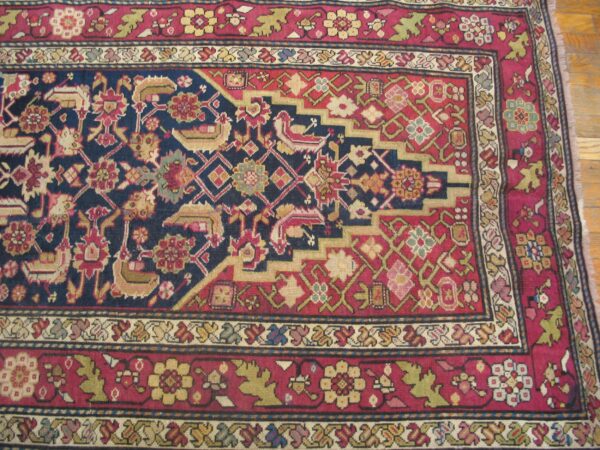 Close-up of a richly patterned rug with a dark blue field and red borders, featuring geometric and stylized floral motifs, by rugs on net