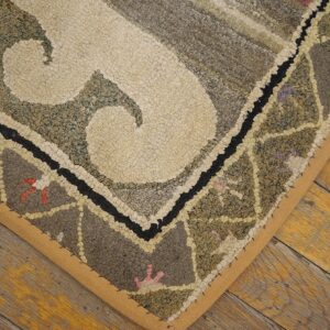Close-up of a hooked rug corner with cream and muted green/grey patterns on a wooden floor by Rugs On Net. by Rugs On Net