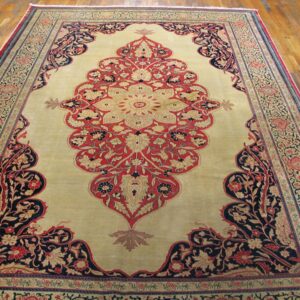 A large, ornate area rug featuring a central medallion in red and beige on a light field, bordered by dark navy and red floral patterns, by Rugs On Net. by Rugs On Net