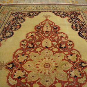 Close-up of a traditional rug with a large central medallion design in red, navy, and cream on a pale yellow field, by Rugs On Net