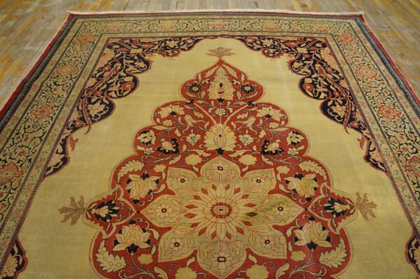 Close-up of a traditional rug with a large central medallion design in red, navy, and cream on a pale yellow field, by rugs on net