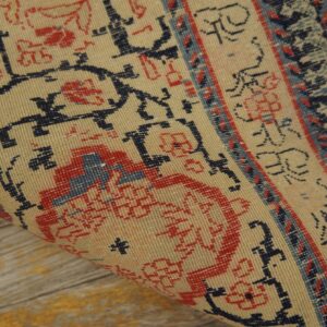 Close-up detail of a beige and red patterned rug corner being rolled, by Rugs On Net