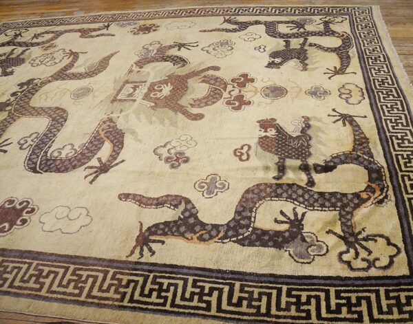 Close-up of an antique chinese rug featuring stylized dragons and clouds on a light field, by rugs on net. By rugs on net
