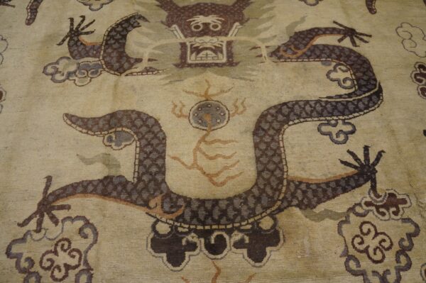 Close-up of a beige rug featuring a detailed, dark brown dragon motif with cloud elements, by rugs on net