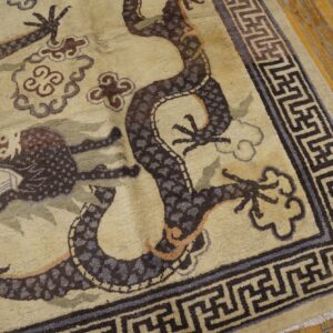 Close-up of a beige rug featuring a dark brown dragon motif and a Greek key border, by Rugs On Net