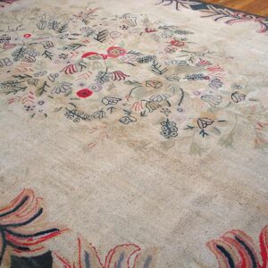 Close-up view of a light-colored rug with scattered floral motifs in muted reds, blues, and greens, featuring a prominent border design, by Rugs On Net