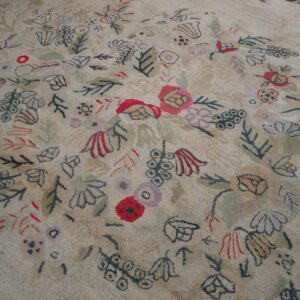 Close-up of a light-colored rug with abstract, scattered floral and leaf motifs in muted colors like red, purple, and dark green, by Rugs On Net