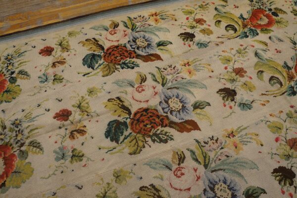 Close-up of a light-colored needlepoint rug featuring a dense, colorful floral pattern with roses and leaves by rugs on net. By rugs on net