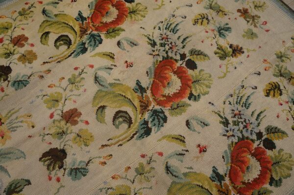 Close-up of a floral needlepoint rug with red roses and green foliage on a cream background by rugs on net