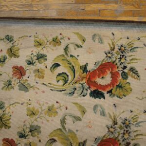 Close-up of a floral needlepoint rug with red and green accents on a light background, by Rugs On Net. by Rugs On Net