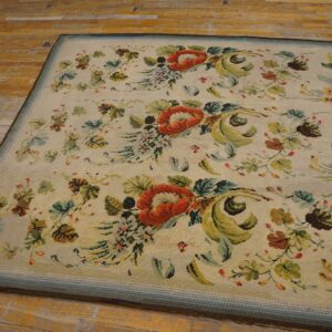 Close-up of a floral needlepoint rug featuring large orange flowers and green foliage on a cream background, by Rugs On Net. by Rugs On Net
