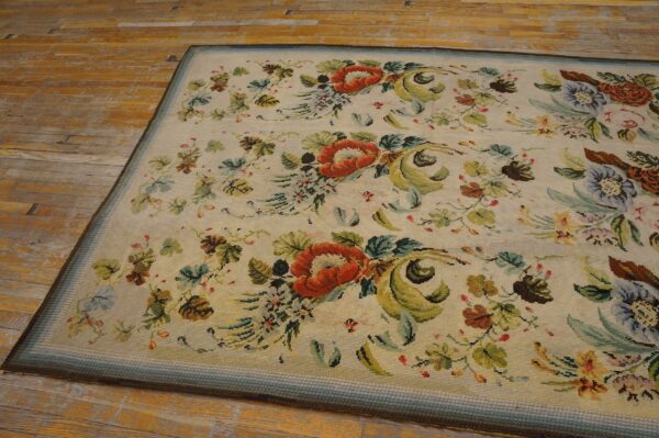 Close-up of a floral needlepoint rug featuring large orange flowers and green foliage on a cream background, by rugs on net. By rugs on net