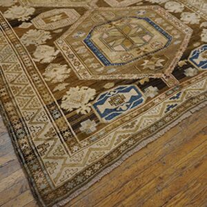 Close-up of a brown and blue patterned rug corner on a wooden floor by Rugs On Net