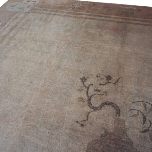 Close-up detail of a faded beige rug with subtle dark brown floral and border motifs, by rugs on net. By rugs on net