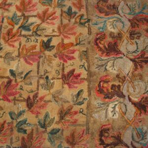 Close-up of a richly textured rug featuring autumnal leaf patterns in reds, greens, and browns on a tan ground, by Rugs On Net