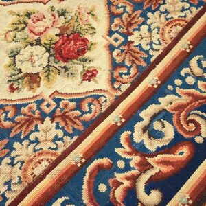 Close-up of a needlepoint rug featuring floral patterns and a blue border, by Rugs On Net