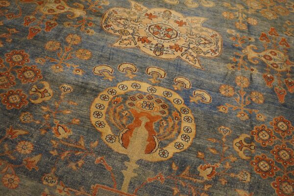 Close-up of a blue field rug with intricate orange and tan floral motifs, including a central stylized animal, by rugs on net