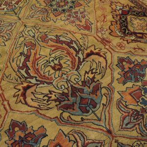 Close-up of an ornate, gold-toned rug with intricate red, blue, and orange floral patterns by Rugs On Net. by Rugs On Net