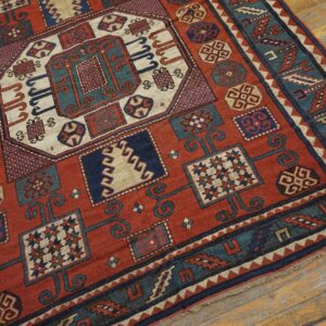 Close-up of a richly patterned antique rug featuring geometric motifs in red, blue, and cream on a wooden floor, by Rugs On Net