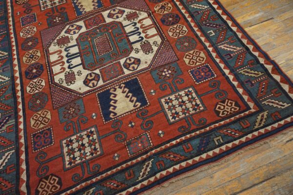 Close-up of a richly patterned antique rug featuring geometric motifs in red, blue, and cream on a wooden floor, by rugs on net