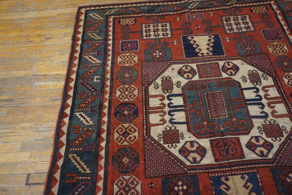 Close-up of a richly patterned red and blue oriental rug on a light wood floor by rugs on net. By rugs on net
