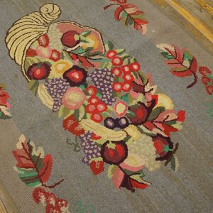 Close-up of a hooked rug featuring a colorful cornucopia overflowing with fruits and surrounded by colorful leaves on a gray background, by Rugs On Net. by Rugs On Net