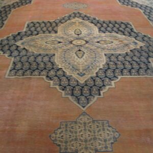Close-up of an antique Persian rug with a central medallion design and salmon field by Rugs On Net
