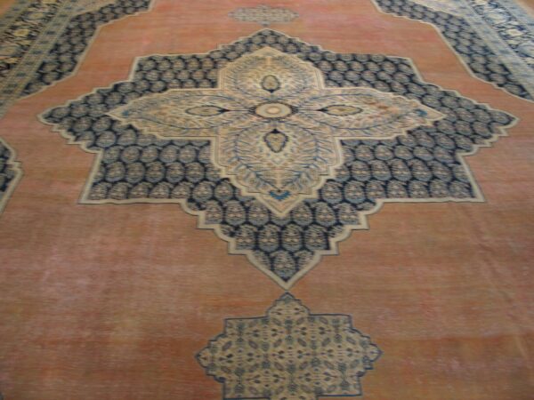 Close-up of an antique persian rug with a central medallion design and salmon field by rugs on net