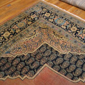 Close-up of the corner and border detail of an antique rug on hardwood flooring by Rugs On Net. by Rugs On Net