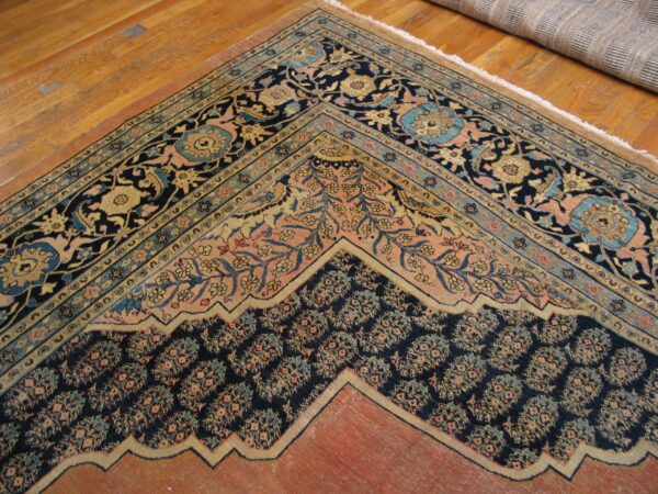 Close-up of the corner and border detail of an antique rug on hardwood flooring by rugs on net. By rugs on net