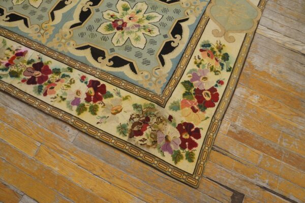Close-up of a floral needlepoint rug corner on distressed wood floors by rugs on net. By rugs on net