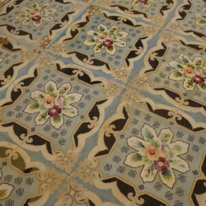 Close-up view of a light blue needlepoint rug with repeating floral medallions by Rugs On Net