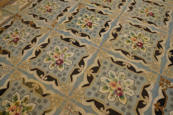 Close-up view of a light blue needlepoint rug with repeating floral medallions by rugs on net
