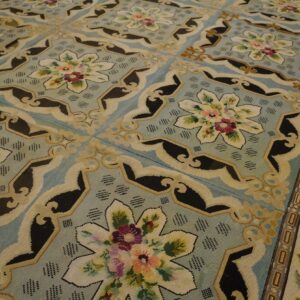 Close-up of a light blue needlepoint rug with floral medallions and black accents by Rugs On Net