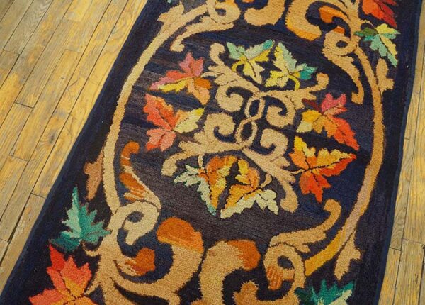 Close-up of a dark blue rug with an ornate central medallion featuring colorful autumn leaves and tan scrollwork, by rugs on net. By rugs on net
