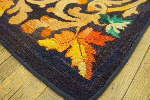 Close-up corner of a dark rug with vibrant orange and yellow maple leaf motifs by rugs on net. By rugs on net