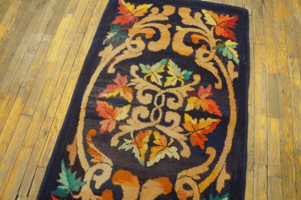 Close-up of the autumn foliage navy runner, showing vibrant autumn-colored leaves and beige scrolling patterns on a dark blue background, resting on wooden floorboards by rugs on net. By rugs on net