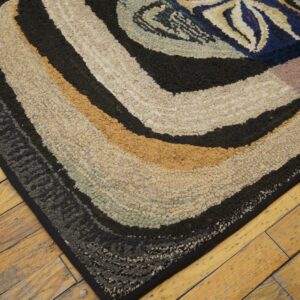 Close-up of the corner of a colorful, textured rug with concentric bands of color on aged wooden floors by Rugs On Net. by Rugs On Net